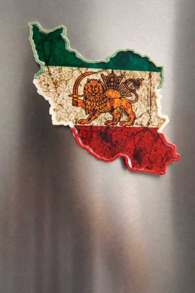 Fridge magnet shaped like a map of iran with a lion emblem on a metallic surface