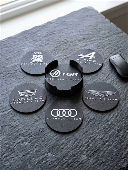 Close-up of Formula 1 team logo coasters set with 3D printed holder on textured surface