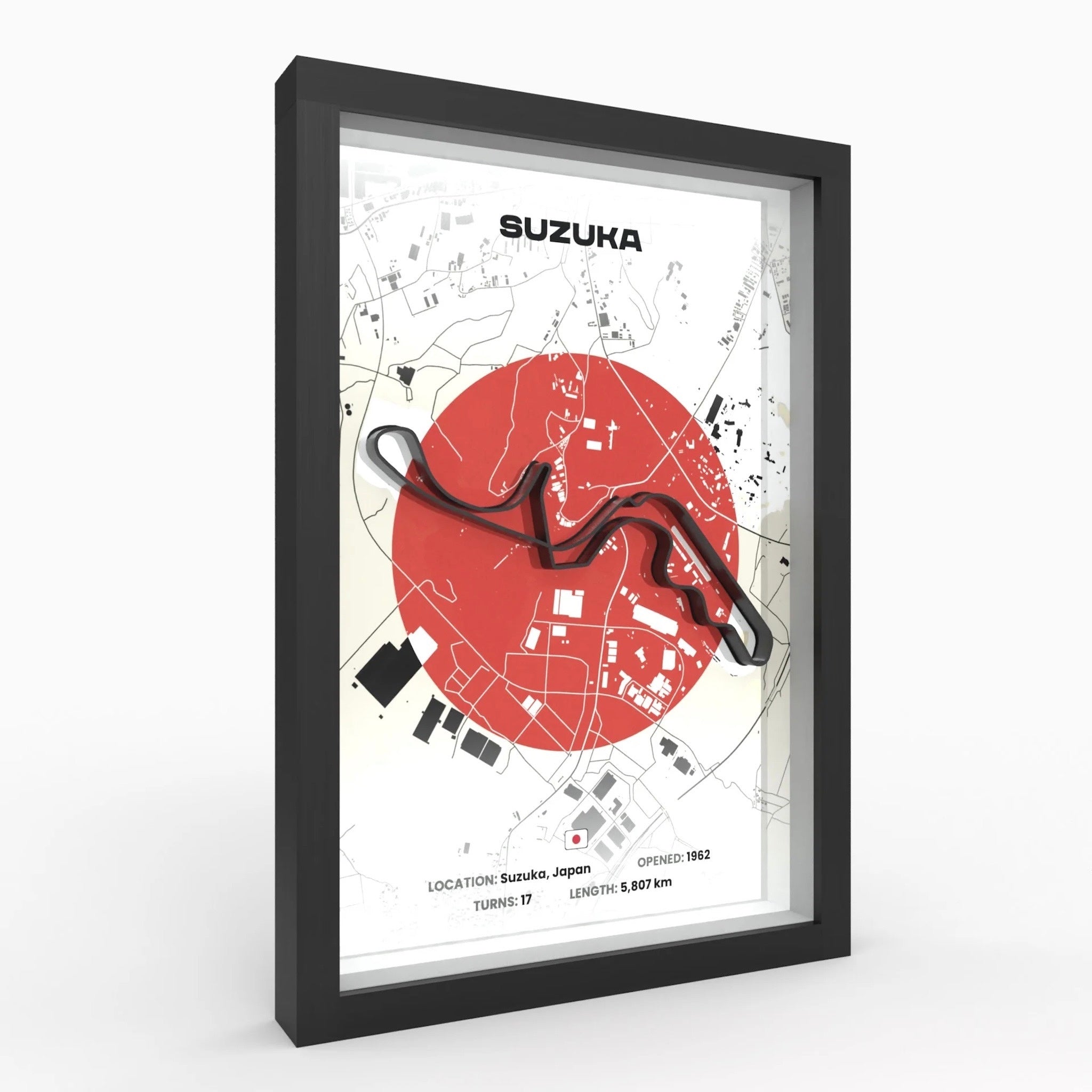 A framed Suzuka race track poster with a black frame, featuring a white background, a large red circle, black track lines, and the word 'SUZUKA' at the top. The frame is shown at a slight angle against a light gray background.
Suzuka Formula 1 track framed 3D wall art front view premium A4