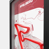 A framed minimalist art print featuring a red and white abstract map design with the name 'SPIELBERG' at the top, shown in a black frame against a light gray background.
Side profile Red Bull Ring track artwork showing elevation layers