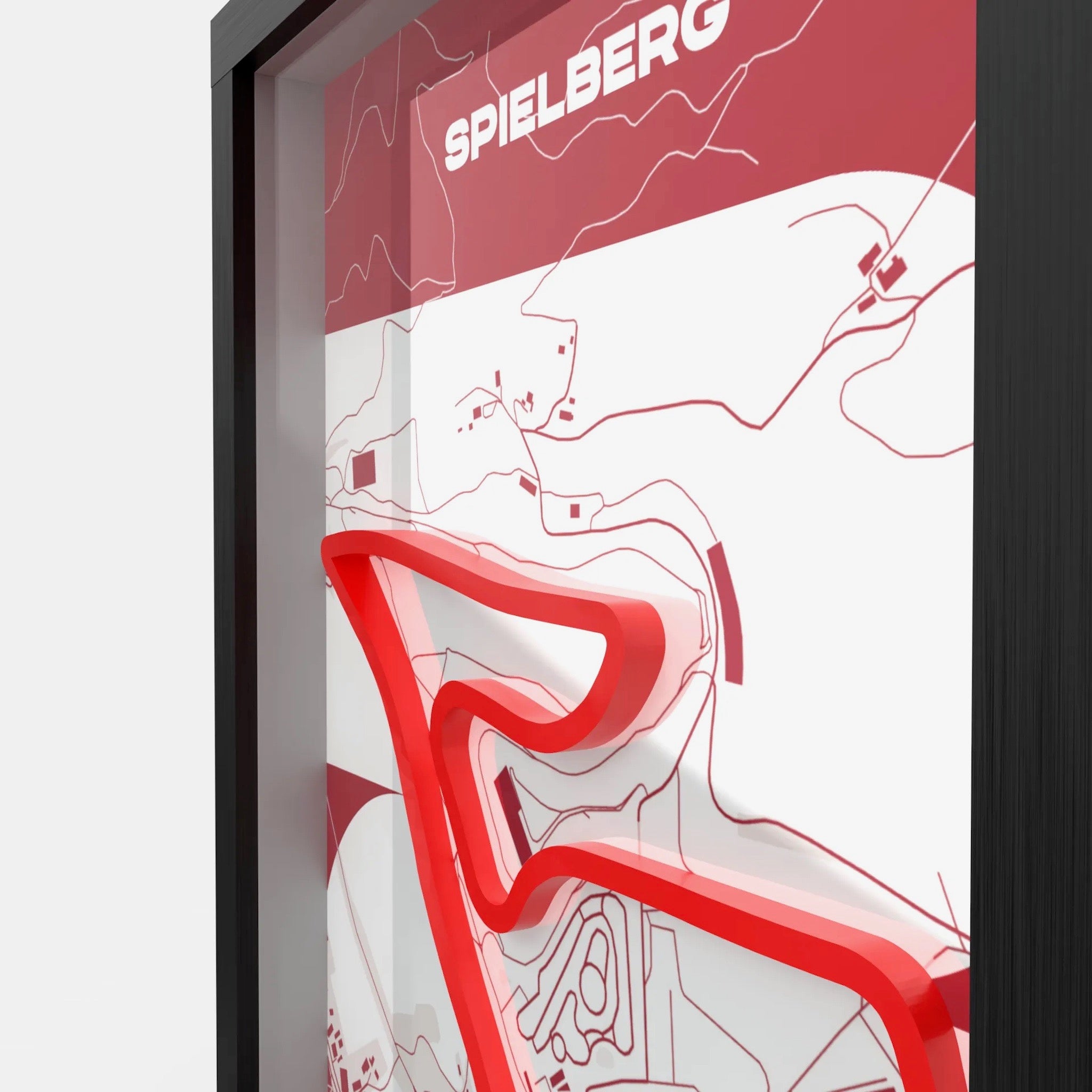 A framed minimalist art print featuring a red and white abstract map design with the name 'SPIELBERG' at the top, shown in a black frame against a light gray background.
Side profile Red Bull Ring track artwork showing elevation layers